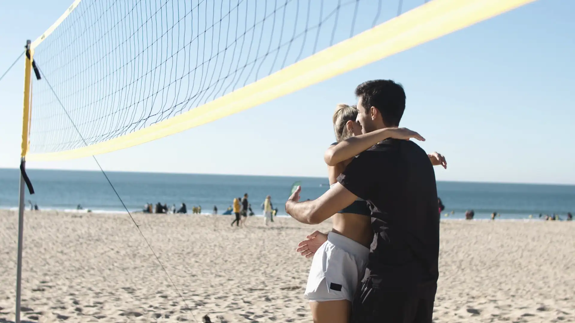Una pareja celebra en la playa con un choque de manos y un abrazo